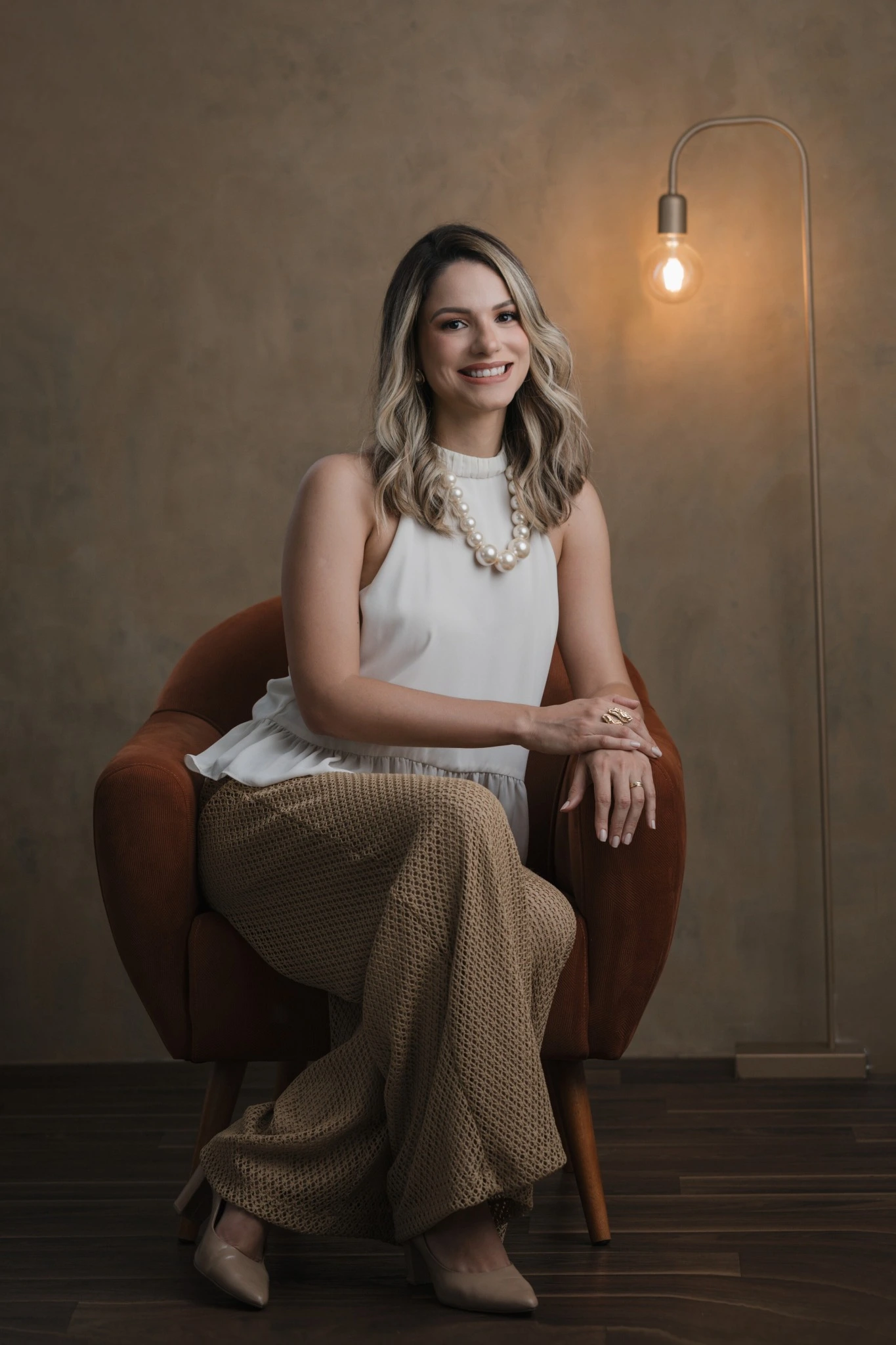 Dra. Letícia Loureiro, sentada em uma poltrona, sorrindo